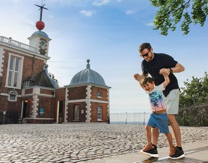 A father and son play on the Prime Meridian Line outside the historic Flamsteed House building of the Royal Observatory