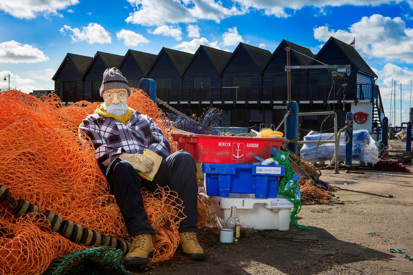 A fisherman puppet sits by the harbor side 