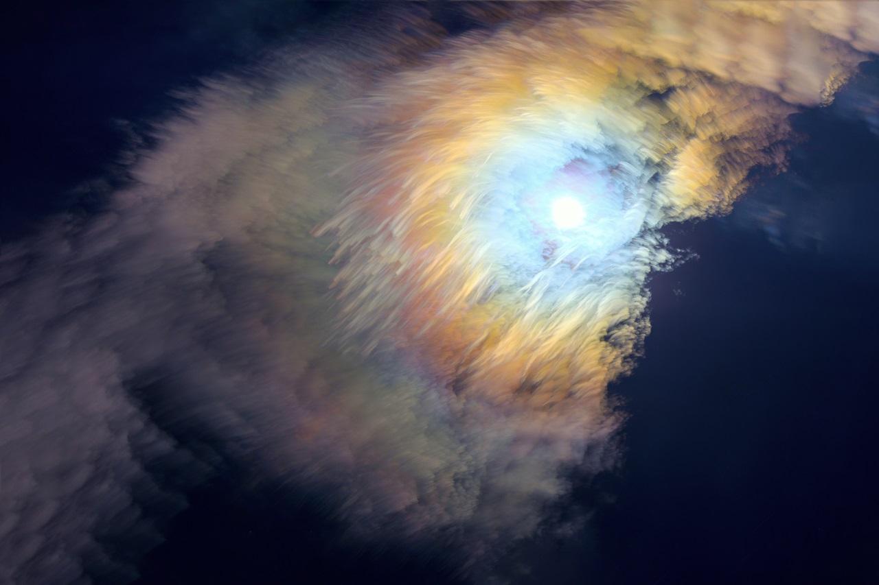 Photograph showing the Moon shining brightly behind clouds