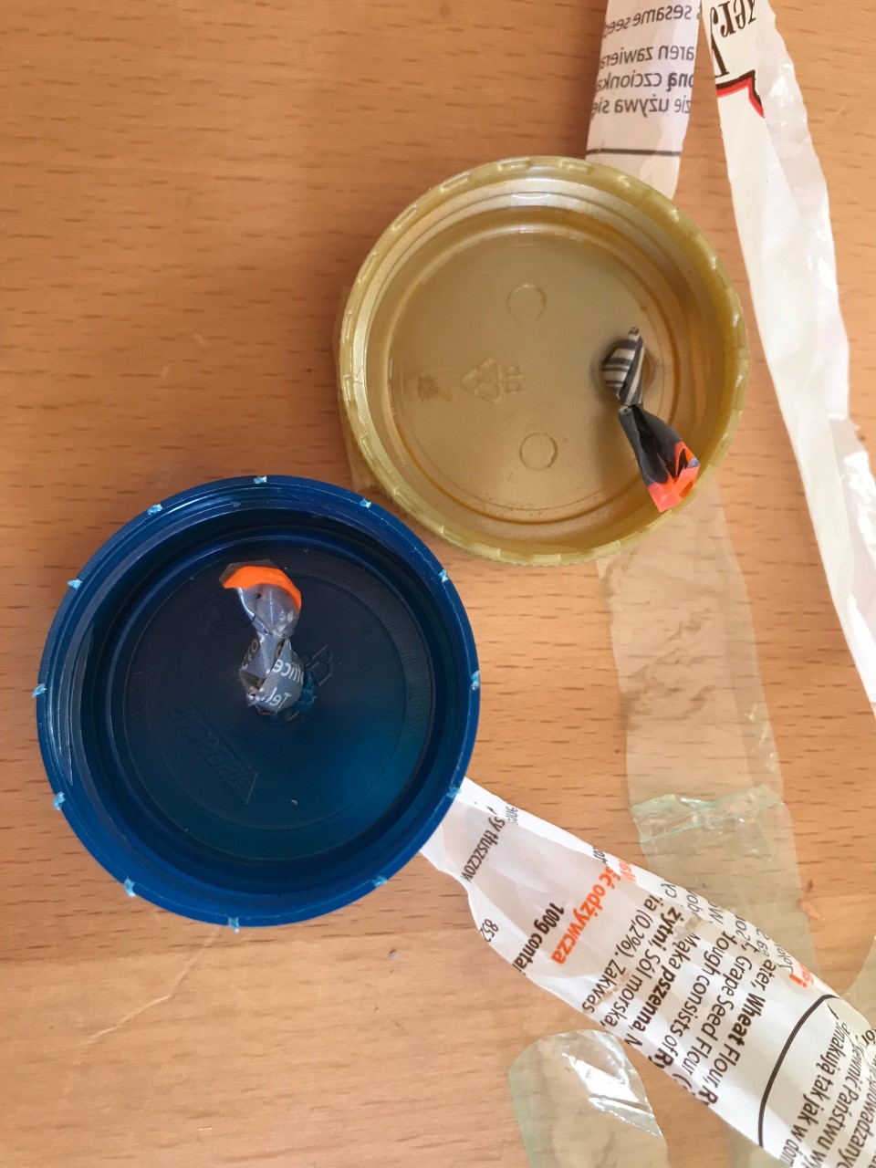 Tie the bottle caps onto the end of the long plastic strips. Two bottle caps with holes in the middle have been tied onto the end of strips of plastic bag