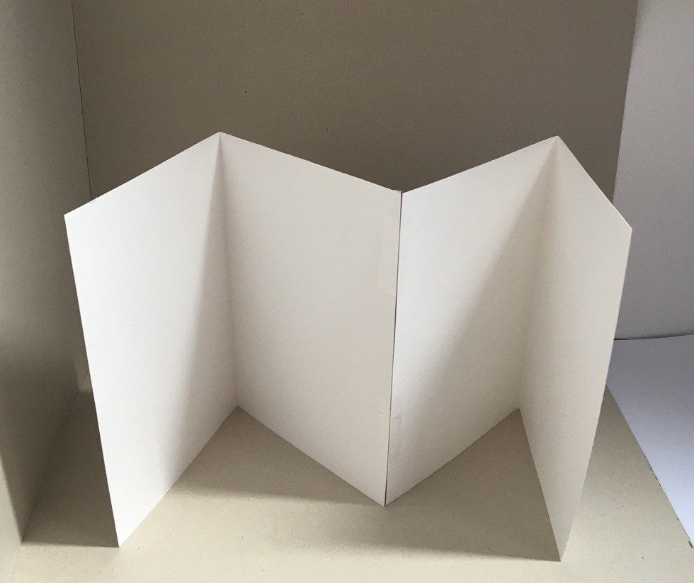 Stick your two pieces of paper together Two pieces of white paper, with a fold crease on each, are stuck together with tape.