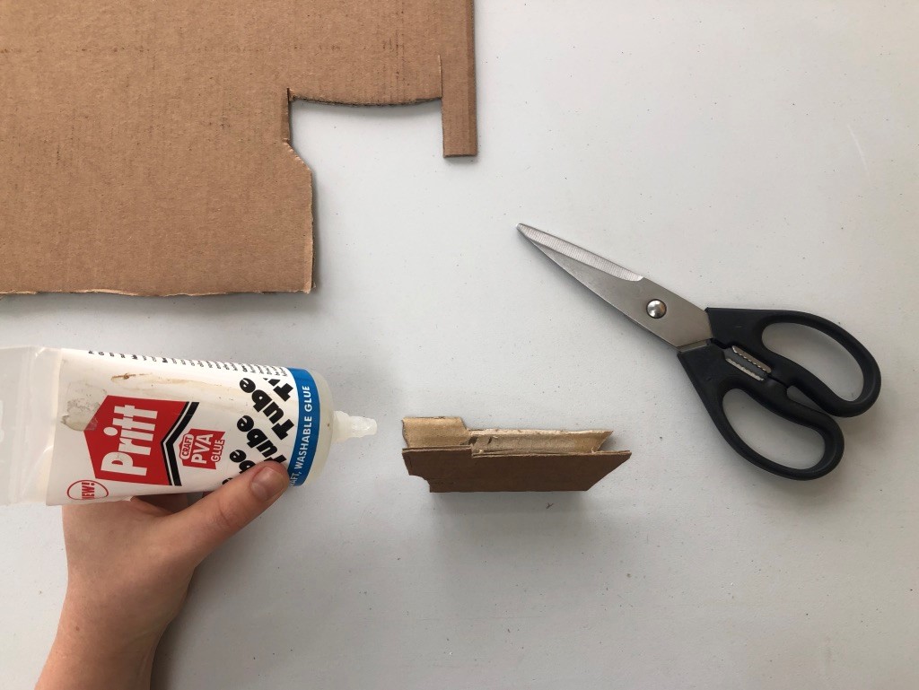 Create the hull of your ship A small ship's hull has been cut out of some cardboard and is being glued together.
