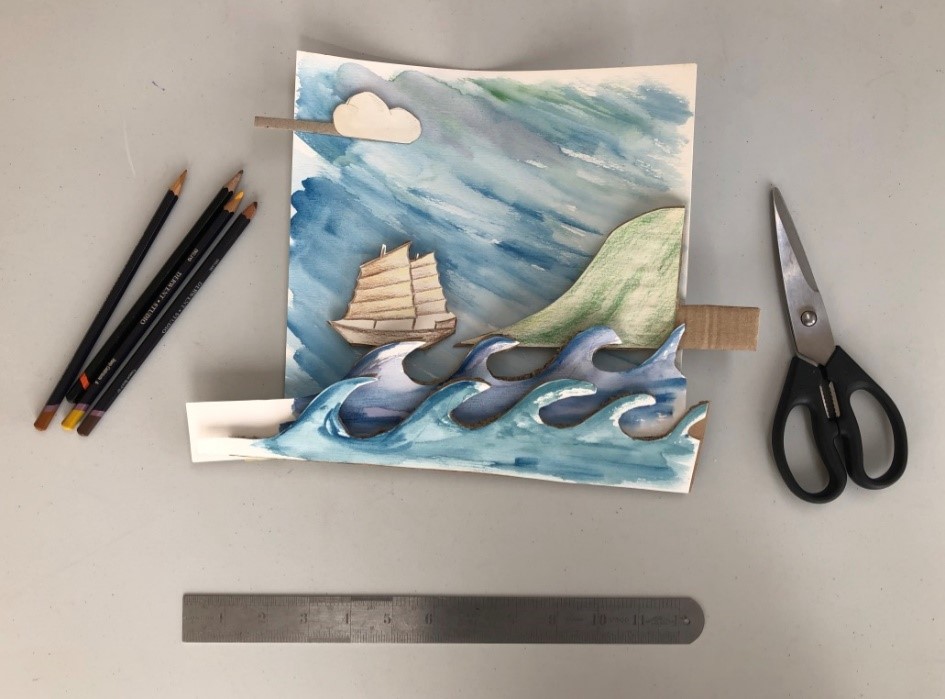 Set your scene A home made craft of a ship at sea is created by painting different sections of the scene and placing one on top of the other. Pencils and scissors lie nearby
