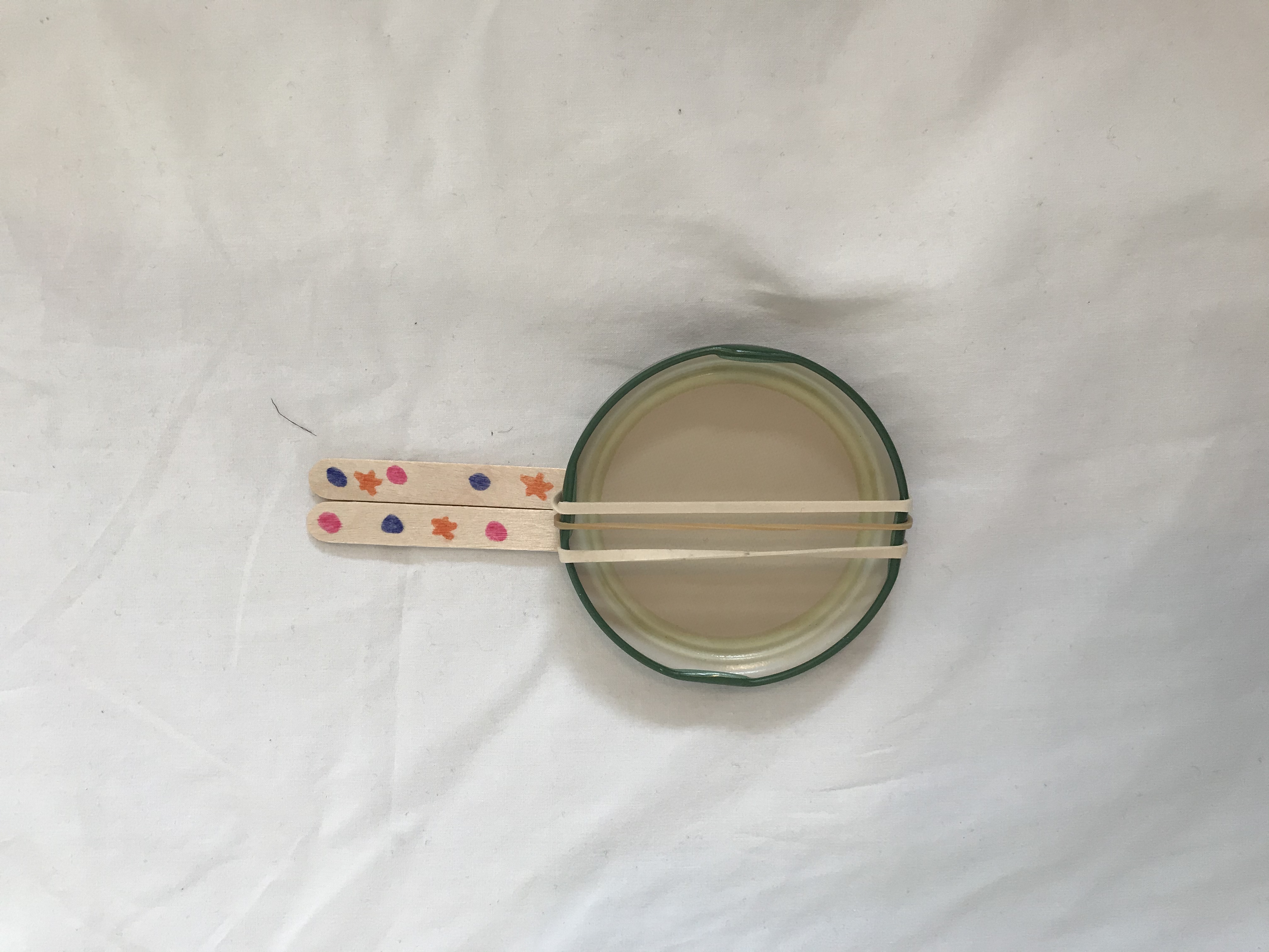 Try making your banjo using a lid instead A mini banjo is made from a jar lid, elastic bands and lollypop sticks.
