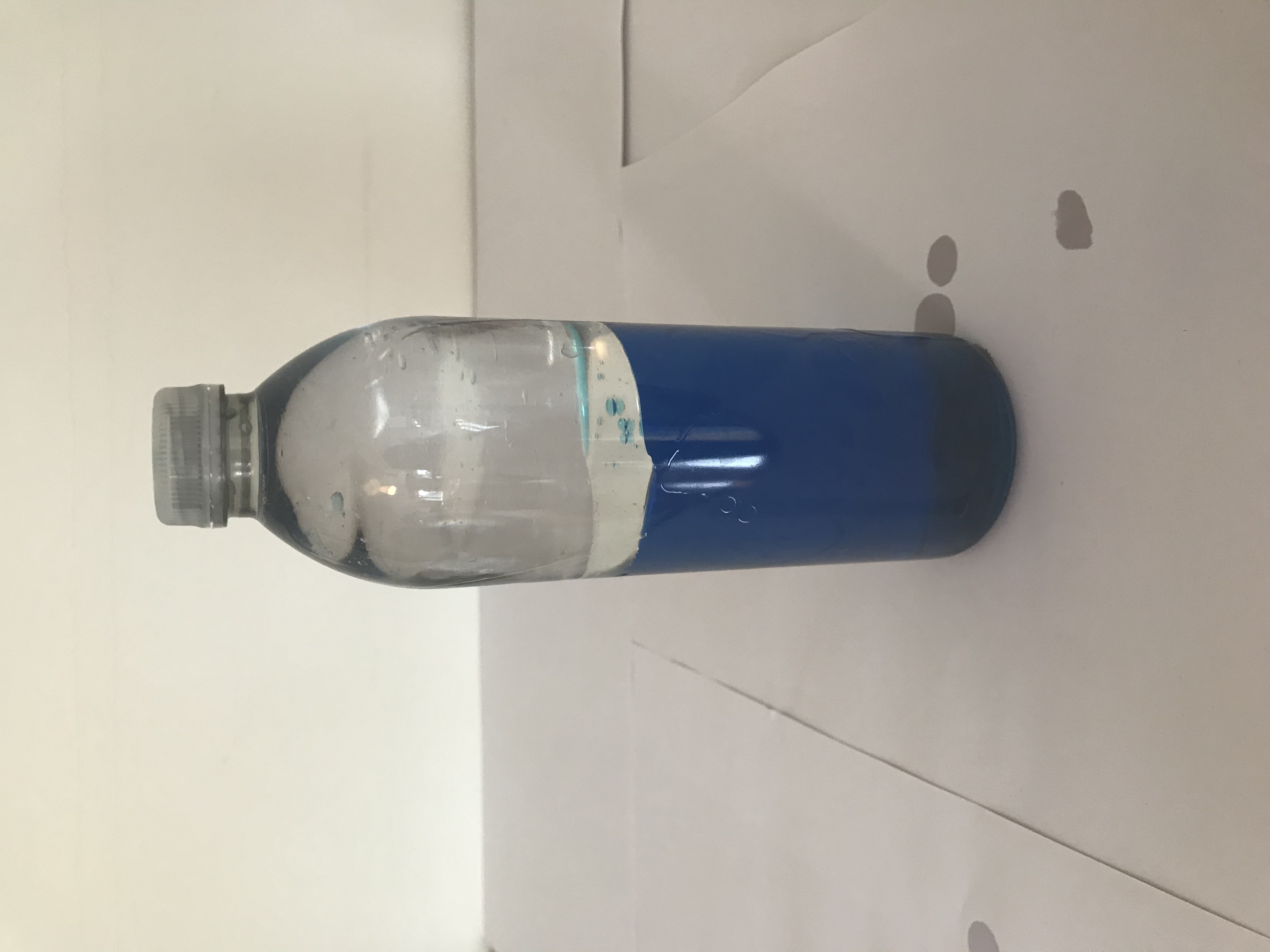 Secure the lid A bottle is half full with dyed blue water. The other half is filled with baby oil.