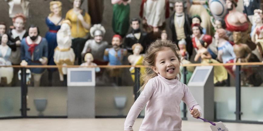 Toddler running in front of the figureheads 