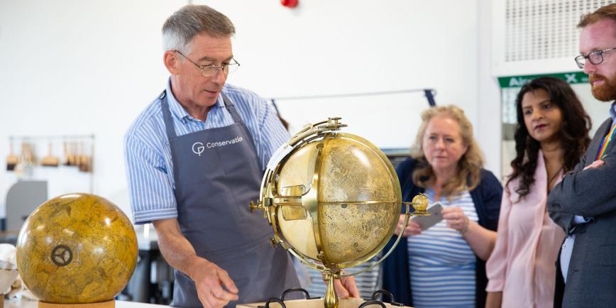 A member of the conservation team shows a tour group a globe