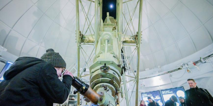 A woman looks through an historic telescope at the Royal Observatory during an evening stargazing event