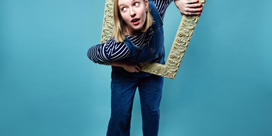 Girl with head and arm through a big gold frame