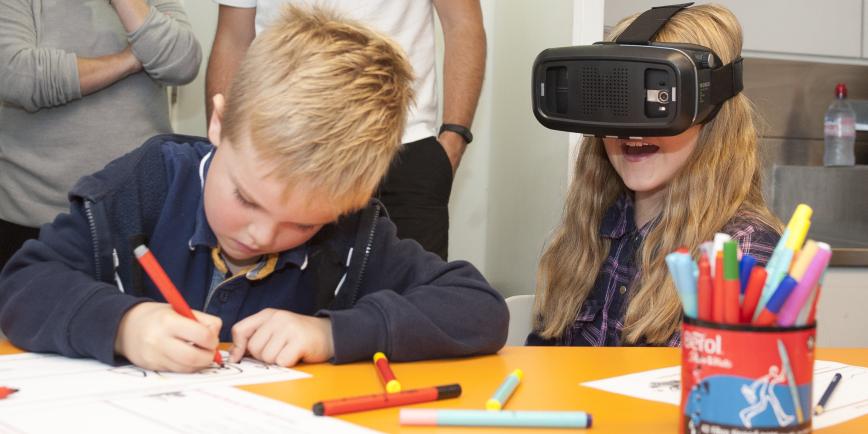 A family workshop at the Royal Observatory, with a boy drawing with a pen and a girl playing with a VR headset