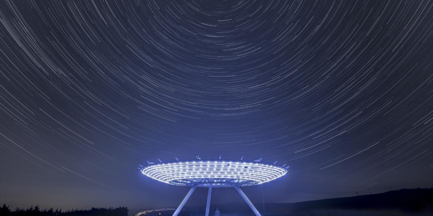 Elevated disk sculpture illuminated by LED lights