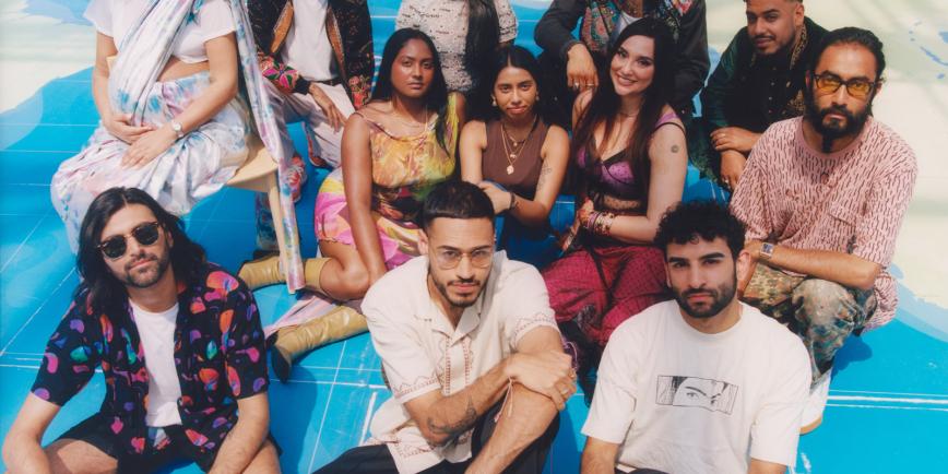 A group portrait photograph of a number of Asian men and women sitting on a giant map. They are all looking up at the camera