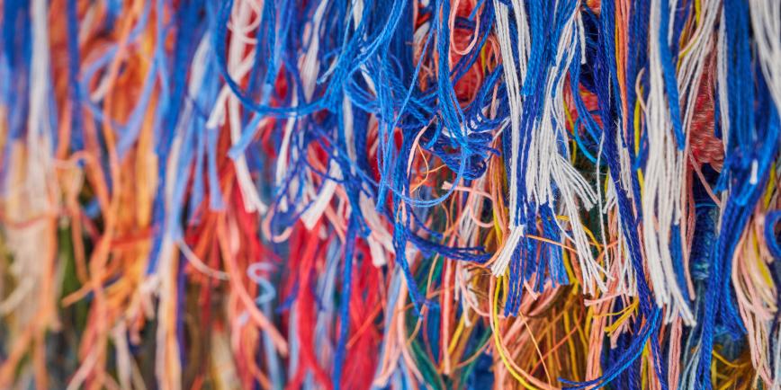 A close-up view of multiple colourful strands of cotton used to weave a tapestry