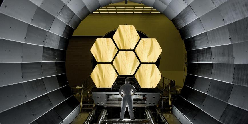 A scientist stands in front of the James Webb Space Telescope during testing