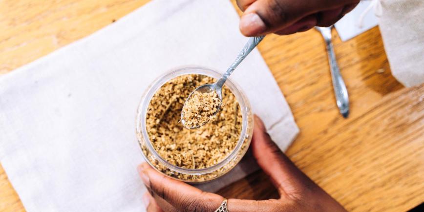 photo of hands holding a jar of herbs and spoon