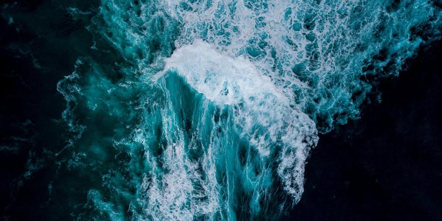 Aerial view of waves crashing in a dark blue sea
