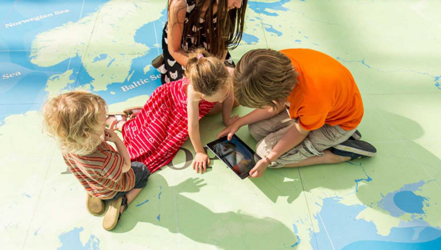 Children playing on a large floor map called the Great Map in the National Maritime Museum