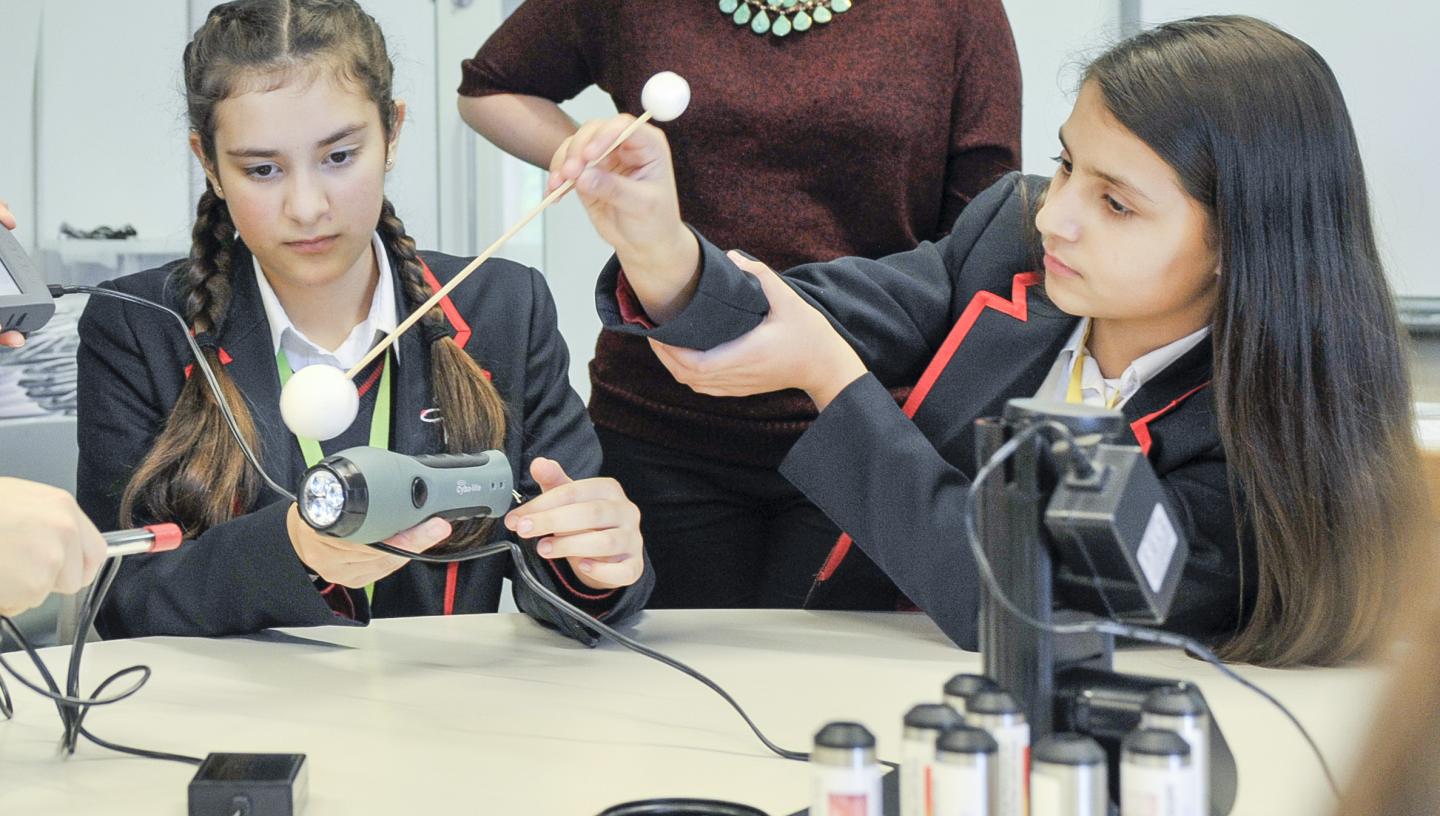 Two students using a stick with a planet ball, light sensor and datalogger to demonstrate the detection of exoplanets through analysing light curves