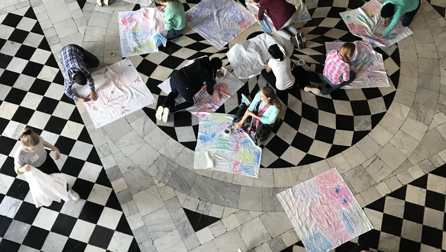 An image of young people drawing onto fabric on the floor of the Queens House