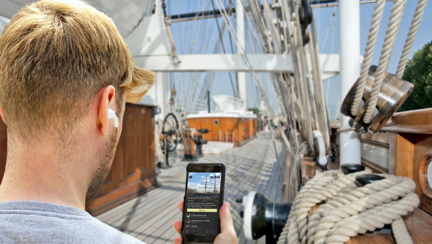 A man follows an audio guide tour of Cutty Sark on his phone