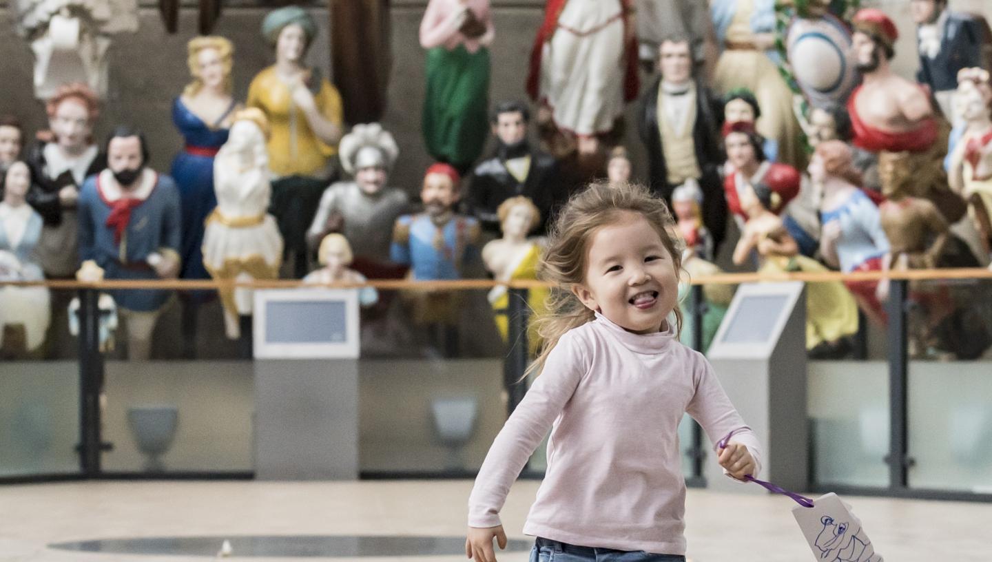 Toddler running in front of the figureheads 