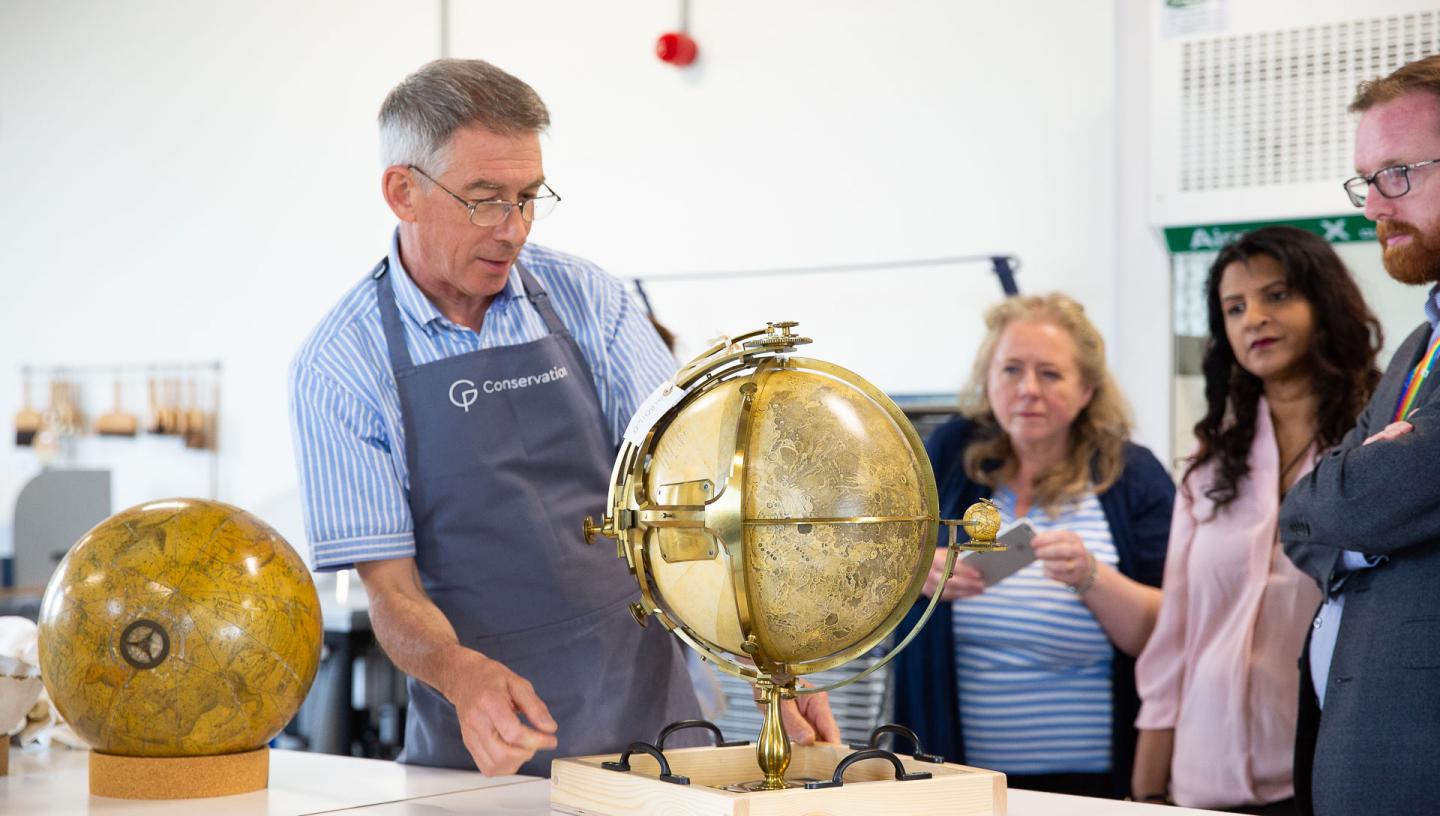 A member of the conservation team shows a tour group a globe