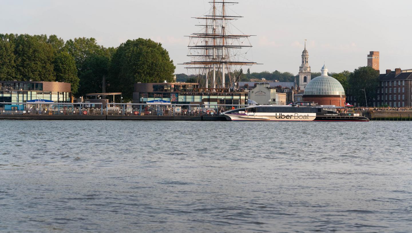 A photograph of the quayside at Greenwich, with a modern ferry service moored in front of the historic ship Cutty Sark