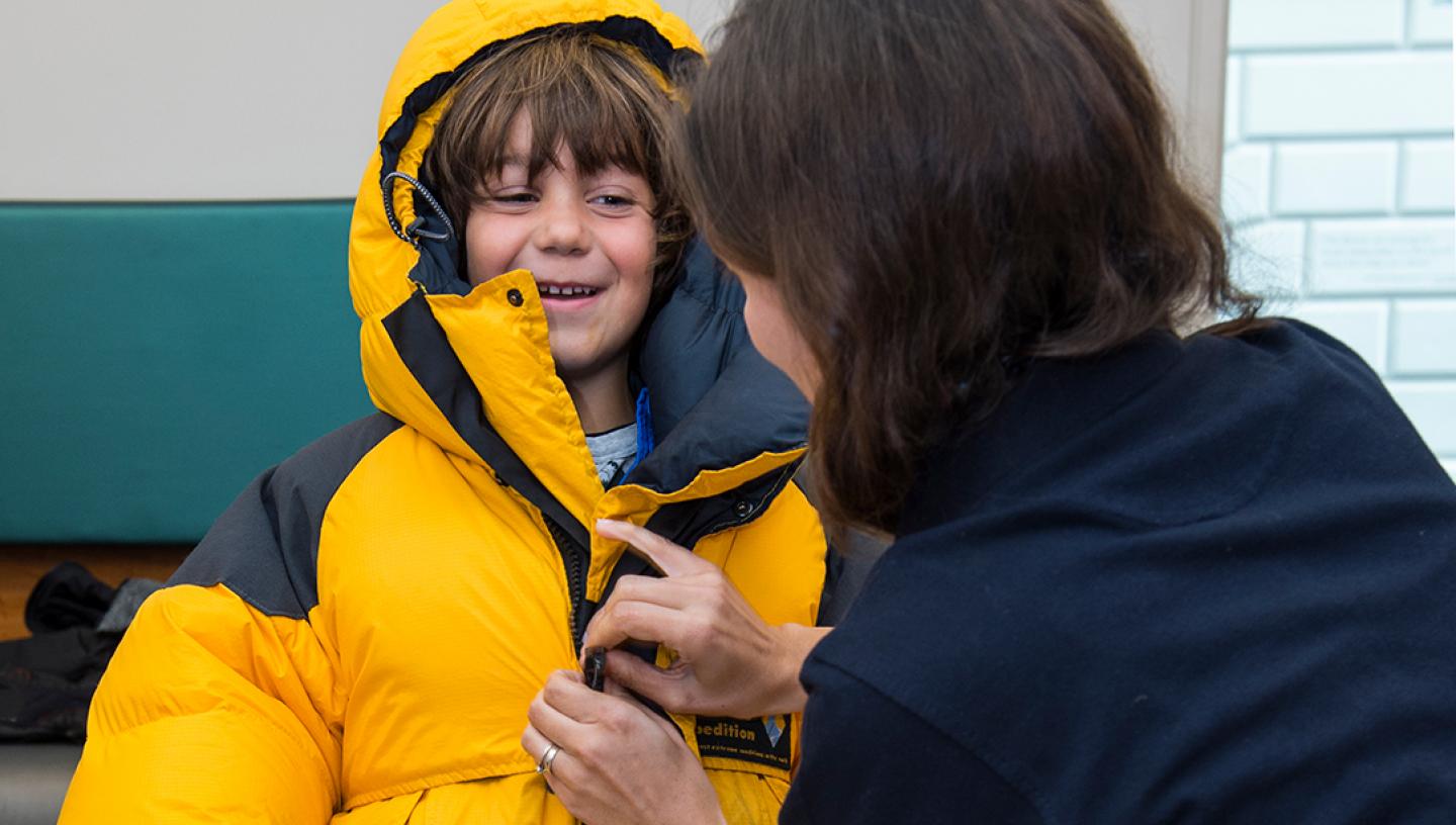 A boy tries out a winter puffer jacket during an event about living in the Antarctic