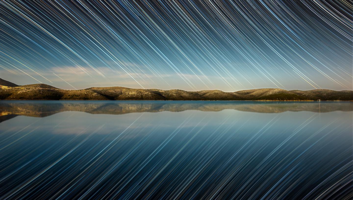 A lake reflecting a sky of stars at twilight