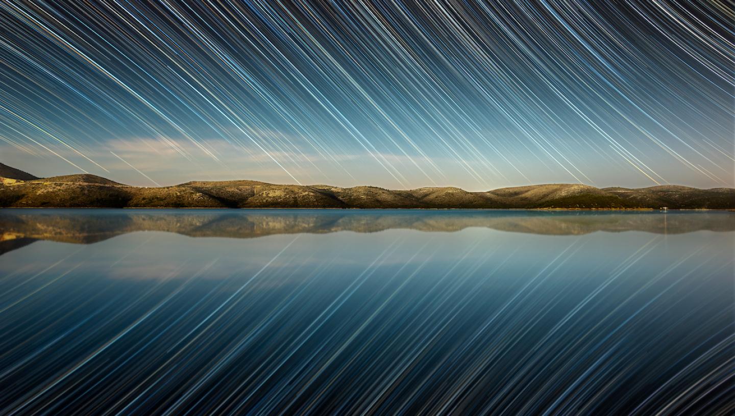A lake reflecting a sky of stars at twilight