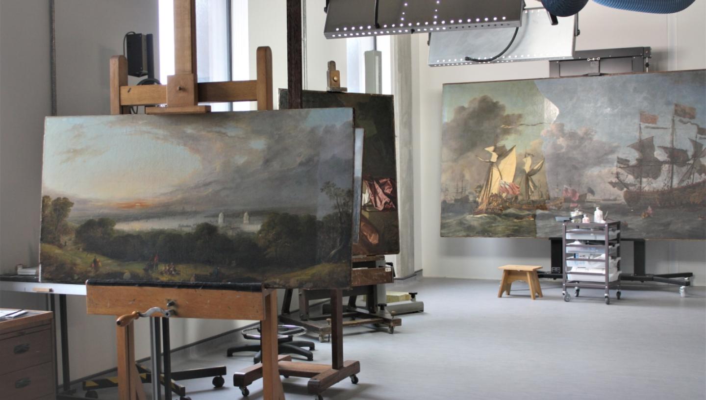 Paintings on easels lined up ready for conservation treatment in the studios of the Prince Philip Maritime Collections Centre