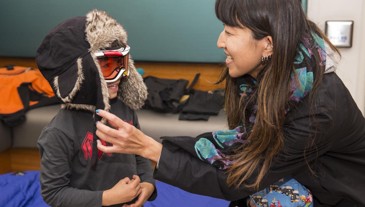 An adult helps a child to get dressed into polar gear