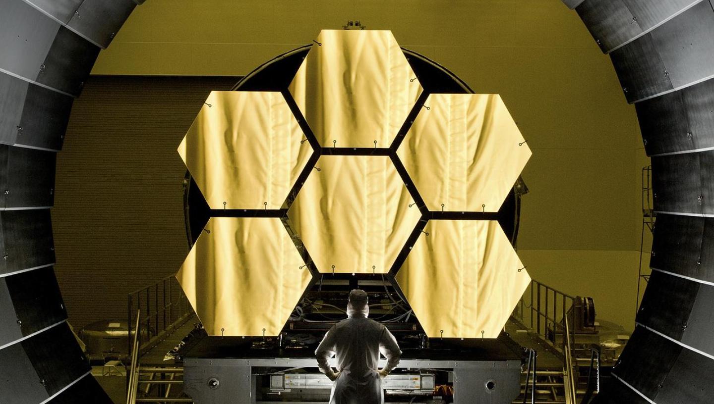A scientist stands in front of the James Webb Space Telescope during testing
