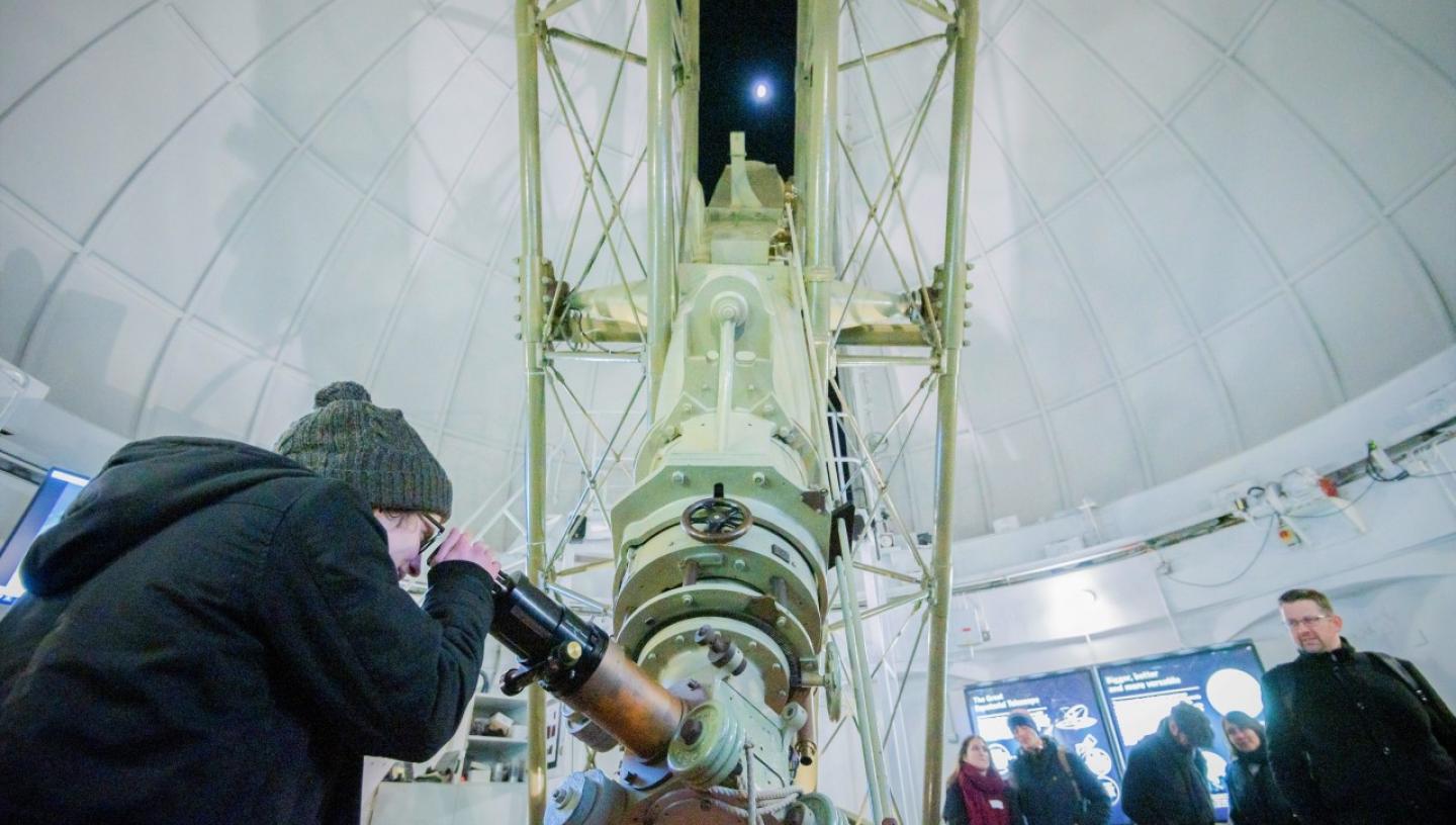 A woman looks through an historic telescope at the Royal Observatory during an evening stargazing event