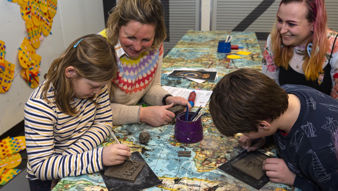 A group of four with adults and children participating in a craft.