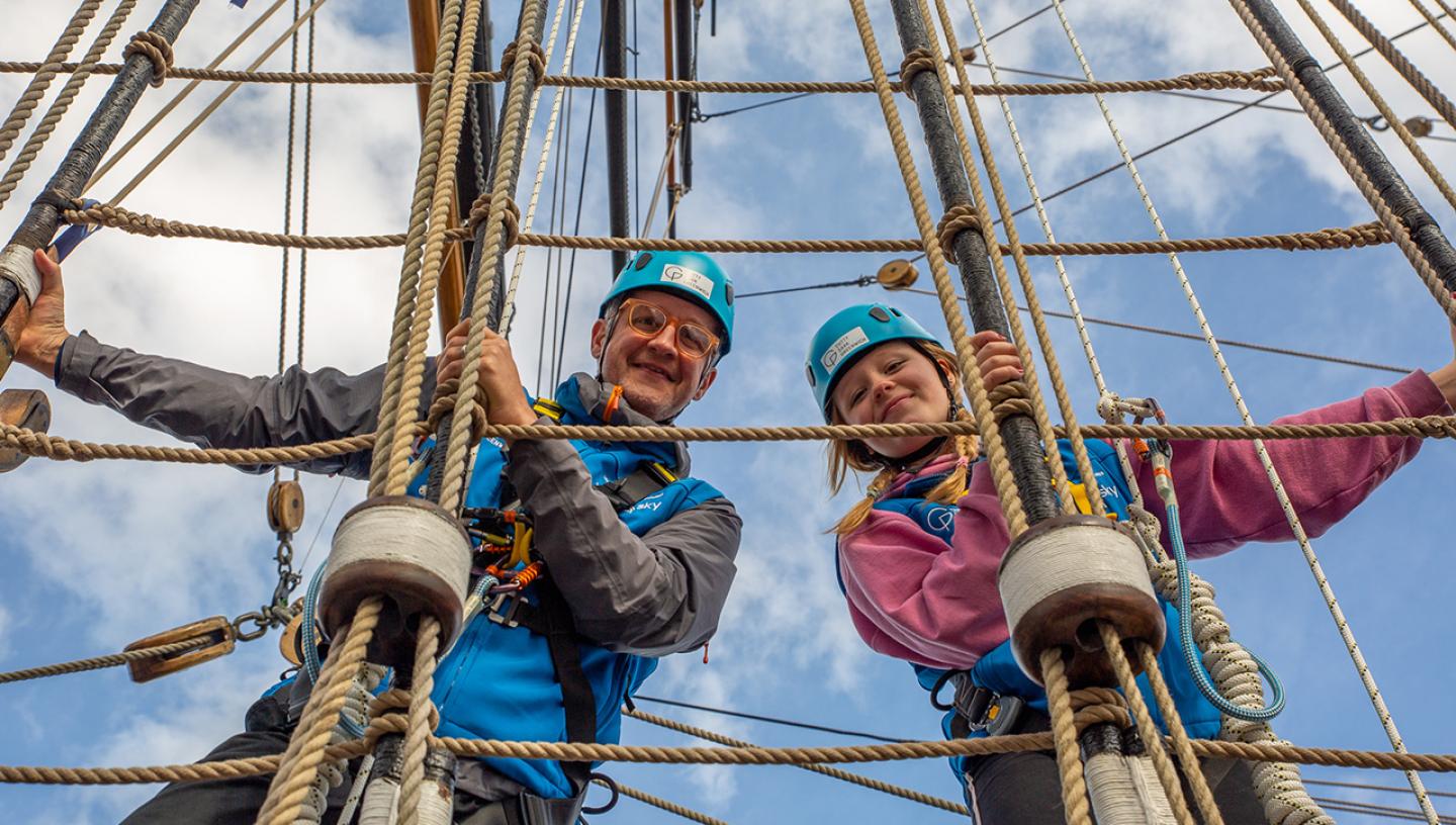 Two people climb the rigging of historic ship Cutty Sark