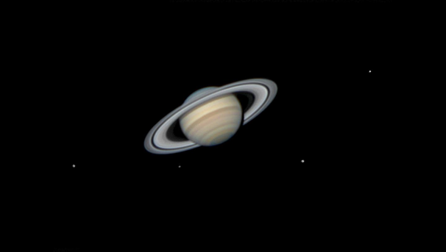 Landscape image with Saturn in the centre and four moons surrounding it