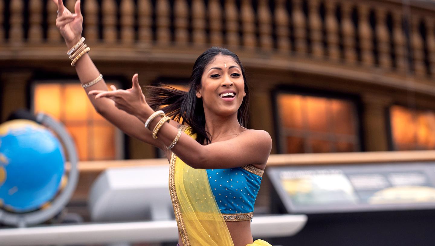 Diwali celebrations at the National Maritime Museum: a South Asian dancer performs in the main space of the Museum, with the stern of a ship in the background