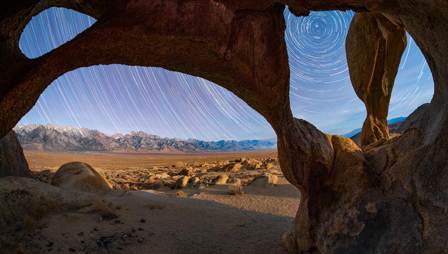 Stars taken through rock arch in mountain range