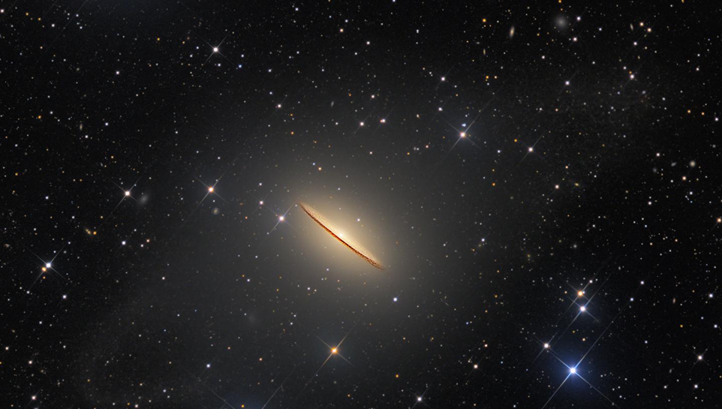 Image of a galaxy side-on, which is golden coloured and resembles a sombrero