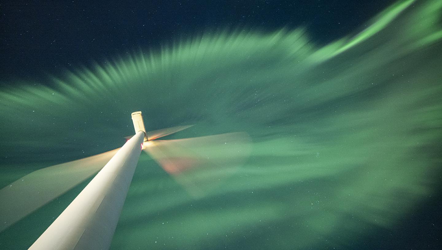 Close up of wind turbine with green aurora above
