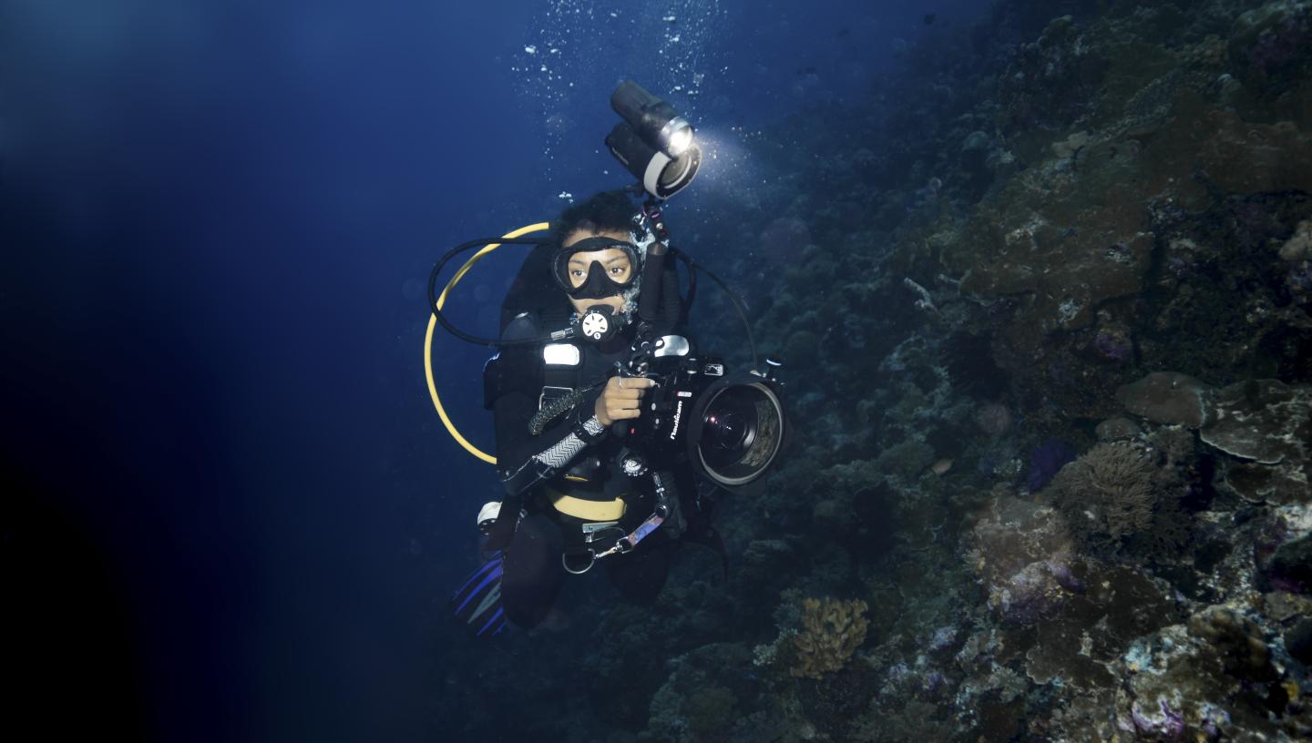 A underwater diver holds a camera