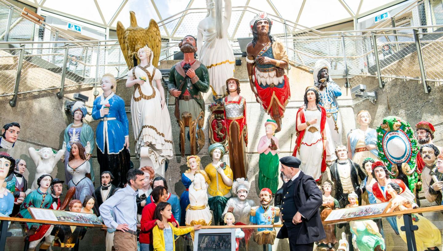 Image of figureheads in Dry Berth of Cutty Sark with a family being talked to by Captain Woodget