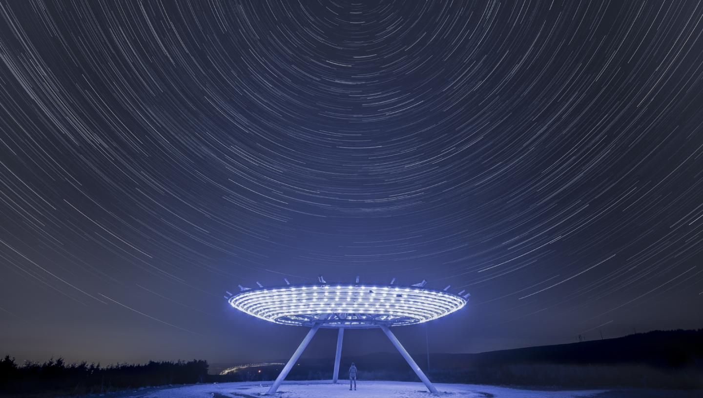Elevated disk sculpture illuminated by LED lights