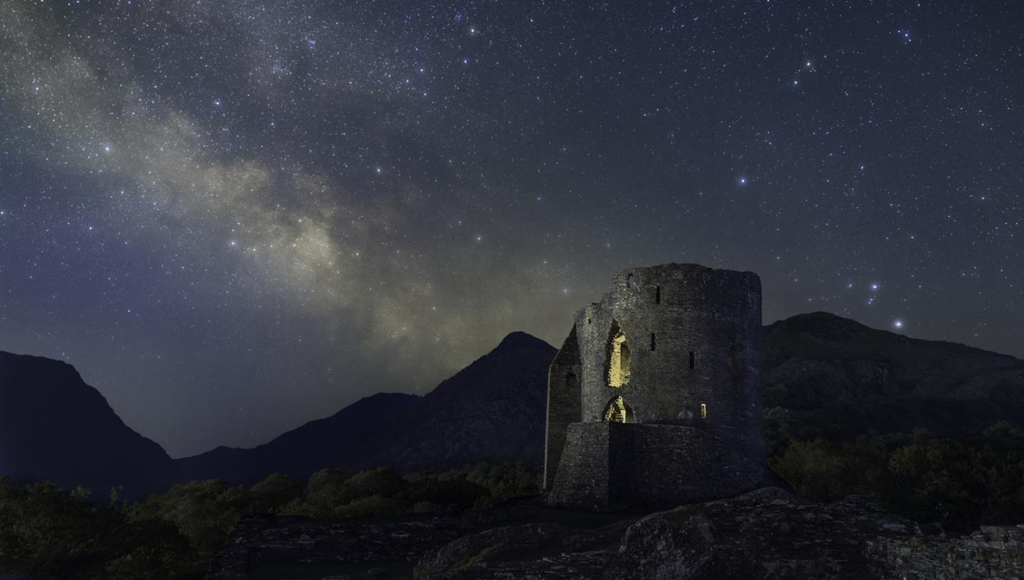 Milky Way rising behind a castle turret in the mountains