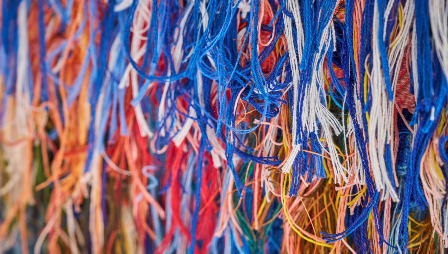 A close-up view of multiple colourful strands of cotton used to weave a tapestry