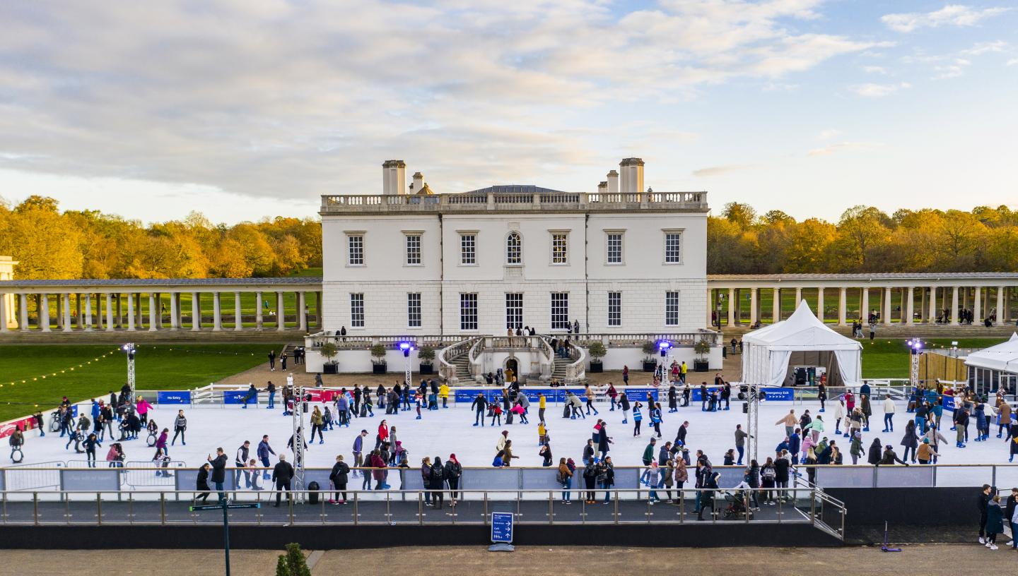 Image of the Queen's House classical building with a big ice rink in front of it with lots of people skating