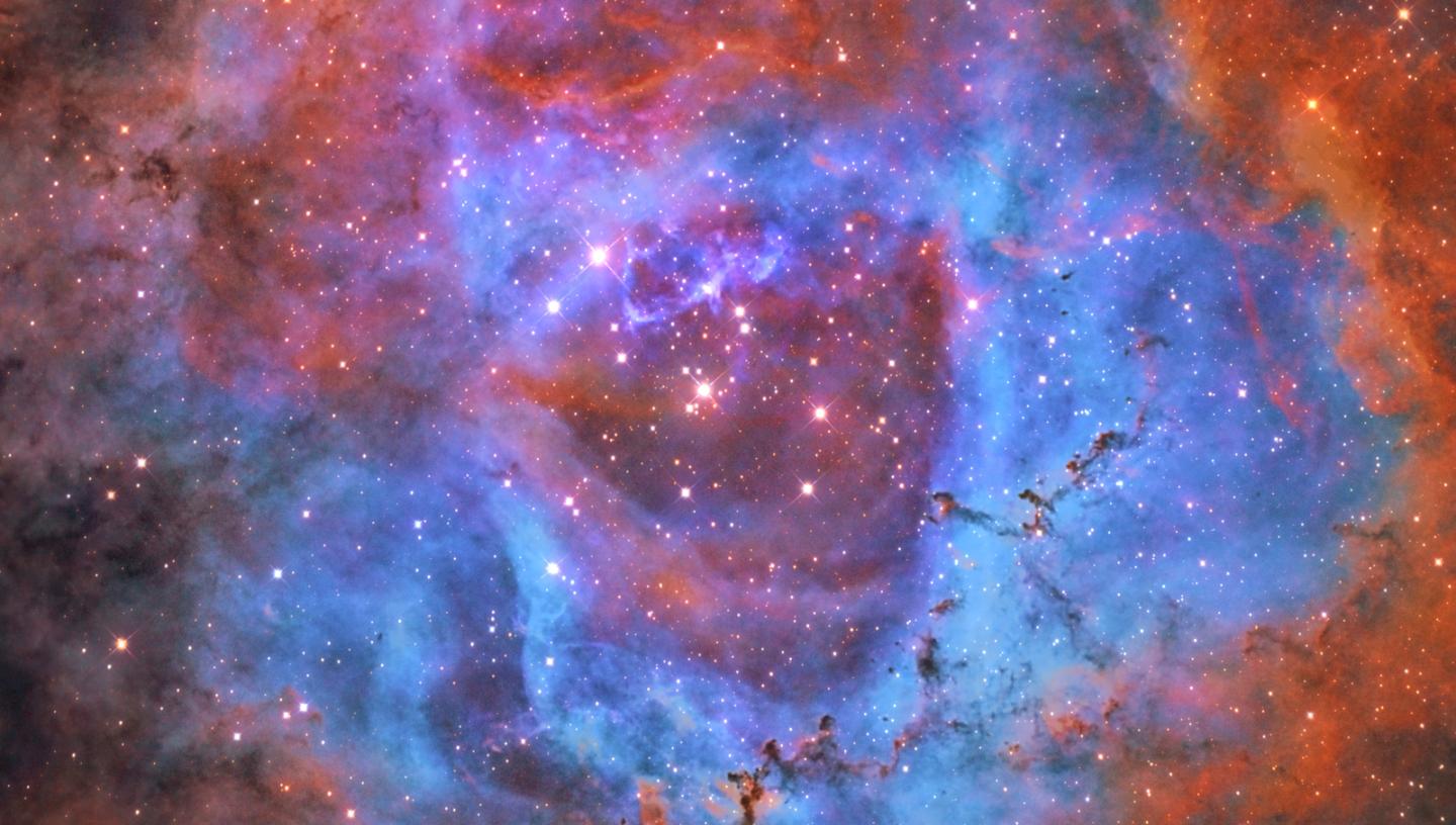 Rosette Nebula surrounded by blue, pink and orange hues