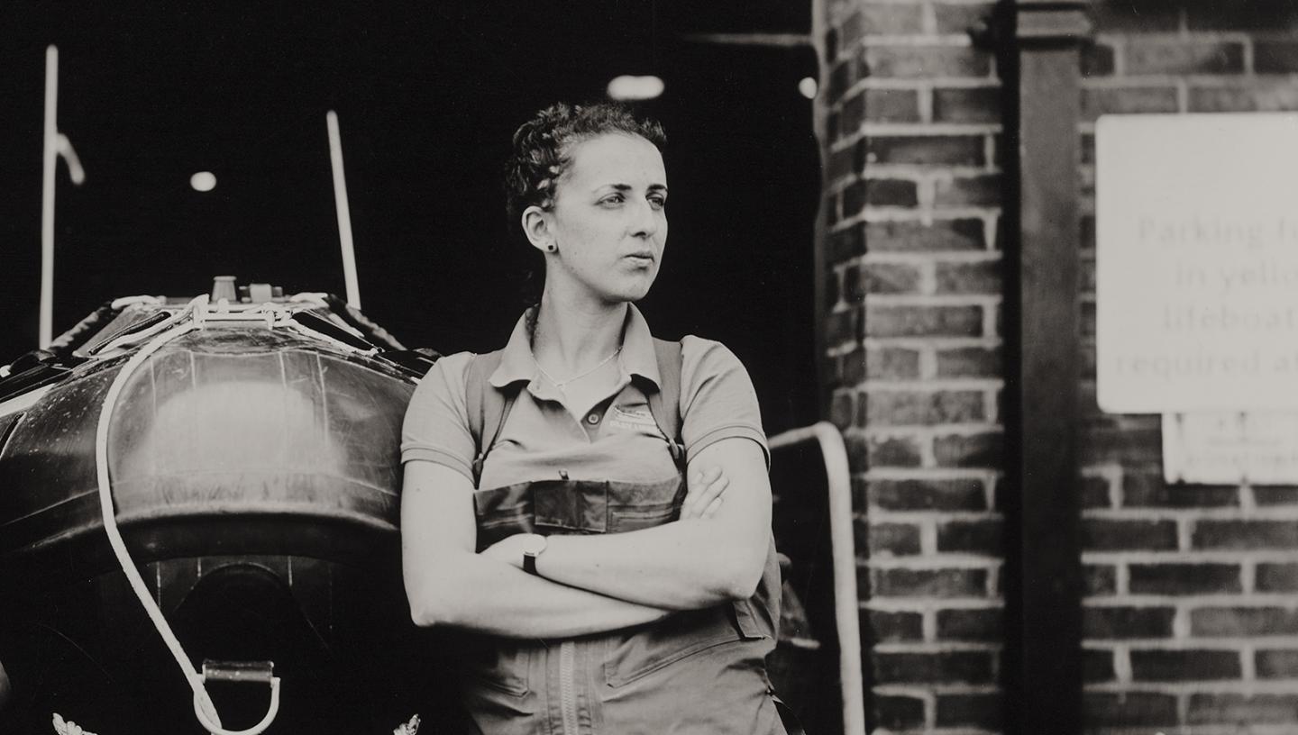 Black and white portrait of a woman leaning against a boat