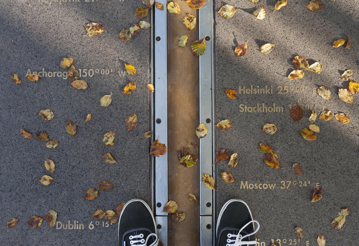 Someone standing with one foot on each side of the Meridian Line